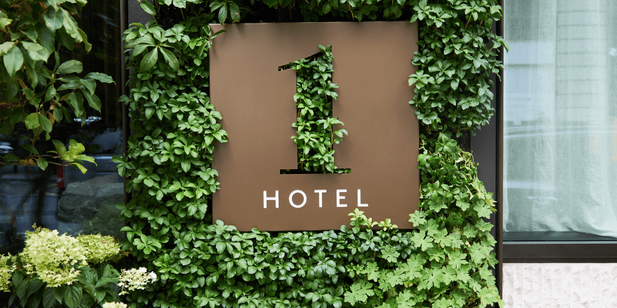 A 1 Hotel sign surrounded by a leafy green wall