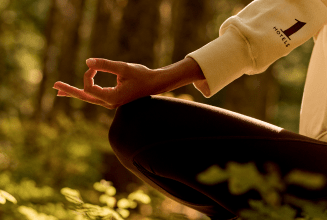 a person sitting down meditating in the forest